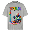 Illustration eines bunten Bären in Regenbogenfarben, der mit Pinsel und Farbpalette kreativ ist, vor dem Berliner Fernsehturm in Regenbogenoptik. Darüber der Schriftzug "Berlin" in Regenbogenfarben und darunter ganz klein "Findickjut". Perfekt zur Feier des CSD Berlin 2025. Oversized Unisex Bio T-Shirt -Grau meliert