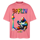 Illustration eines bunten Bären in Regenbogenfarben, der mit Pinsel und Farbpalette kreativ ist, vor dem Berliner Fernsehturm in Regenbogenoptik. Darüber der Schriftzug "Berlin" in Regenbogenfarben und darunter ganz klein "Findickjut". Perfekt zur Feier des CSD Berlin 2025. Oversized Unisex Bio T-Shirt - Pink 