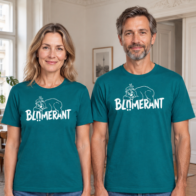 Mann und Frau tragen ozeanblaue T-Shirts mit weißem BLÜMERANT-Schriftzug und Bärenmotiv in einer Berliner Altbauwohnung.