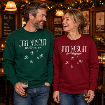 Lachendes Paar in einer weihnachtlich geschmückten Berliner Kneipe: Mann im grünen und Frau im burgunderroten  Bio-Sweater mit weißem „JIBT NÜSCHT, ihr Flitzpiepen“-Weihnachtsmotiv und Geschenk-Illustrationen.