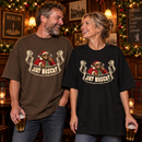 Lachendes Paar zwischen 45 und 60 Jahren in einer weihnachtlich geschmückten Berliner Kneipe: Der Mann trägt ein braunes, die Frau ein schwarzes Oversize-Bio-T-Shirt mit Santa-Bär-Motiv und dem Schriftzug „JIBT NÜSCHT“.