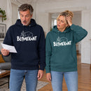 Mann und Frau in dunkelblauem und petrolfarbenem BLÜMERANT-Hoodie mit weißem Bärenmotiv in einer Berliner Wohnung. Er starrt mit offenem Mund auf einen Brief, sie hält sich schwindelig die Hand an die Schläfe.