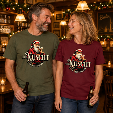 Lachendes Paar in einer weihnachtlich geschmückten Berliner Kneipe: Mann im khaki-grünen und Frau im burgunderfarbenenBio-T-Shirt mit Berliner Gangster-Weihnachtsmotiv, rauchendem Weihnachtsmann und dem Schriftzug „JIBT NÜSCHT, ihr Flitzpiepen“.