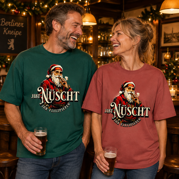 Lachendes Paar in einer weihnachtlich geschmückten Berliner Kneipe: Mann im grünen und Frau im erdroten  Bio-T-Shirt mit Berliner Gangster-Weihnachtsmotiv, rauchendem Weihnachtsmann und dem Schriftzug „JIBT NÜSCHT, ihr Flitzpiepen“.
